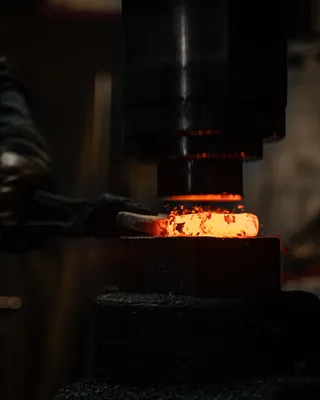 Blacksmith hammering a glowing red-hot piece of iron