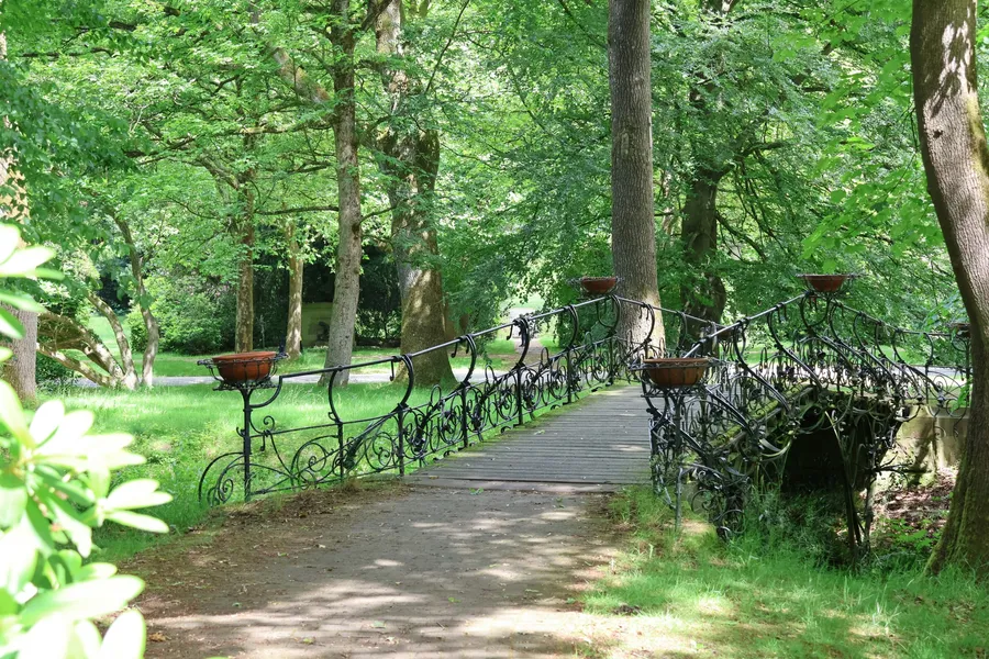 Passerelle en fer forgé prenant appui sur ses deux rives, au-dessus d’un ruisseau
